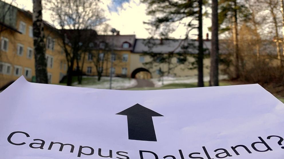 Papper med pil och texten ”campus dalsland” pekar mot en gul stenbyggnad