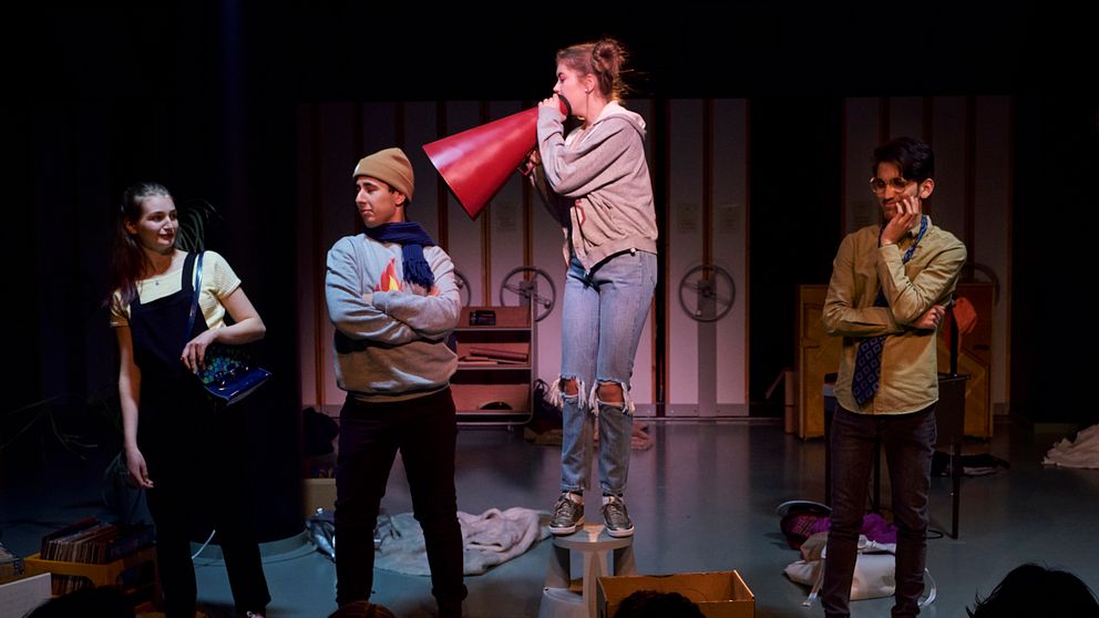 Fyra stycken ungdomar står på en scen och spelar teater.