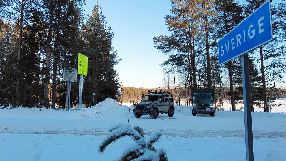 sverigeskylt med militärfordon i bakgrunden