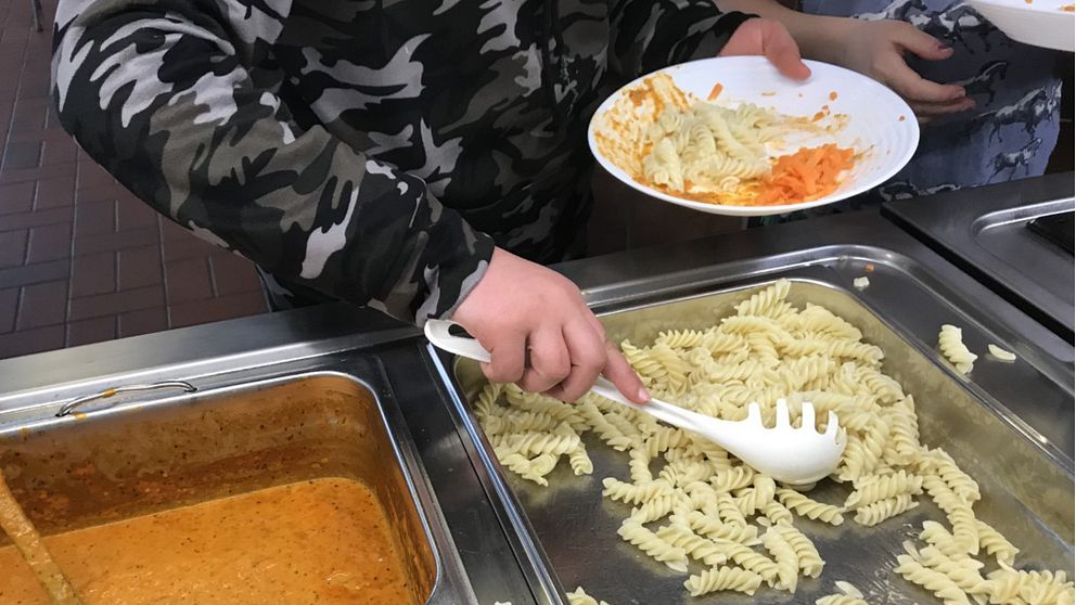 Barn som tar mat i skolmatsalen