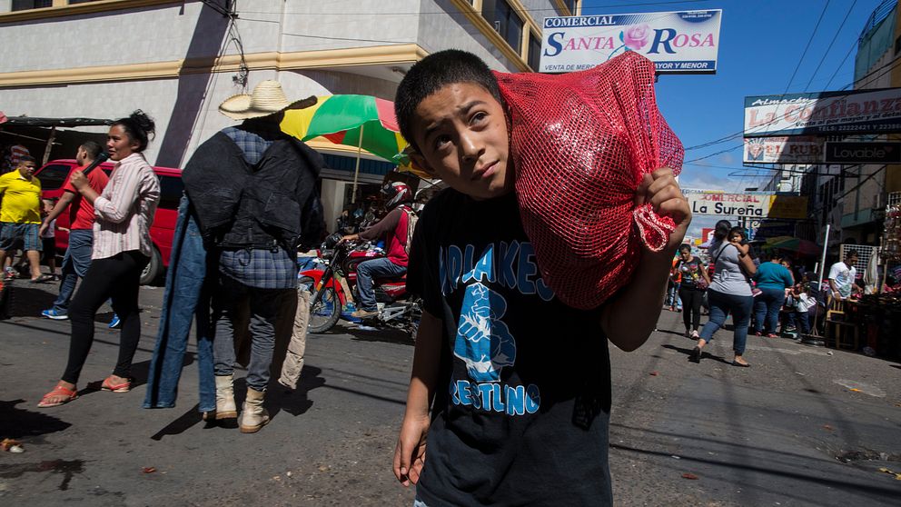 En pojke bär på en säck med grönsaker vid en marknad i Tegucigalpa i Honduras. Arkivbild.