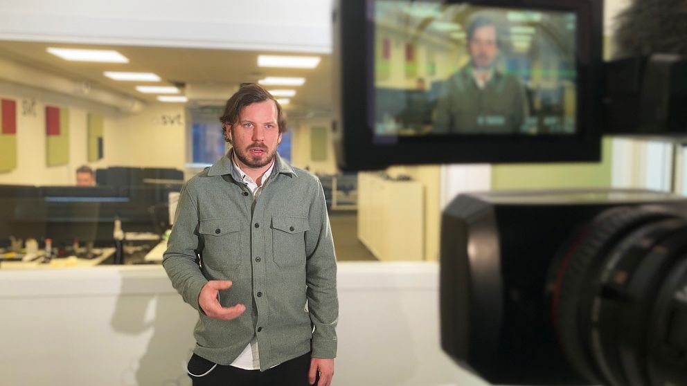Albin Aghamn står framför en kamera på SVT Sörmland:s redaktion. I bakgrunden syns ett kontorslandskap.