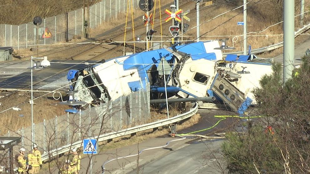 Mycket illa kvaddad buss ligger på järnvägsspåret.