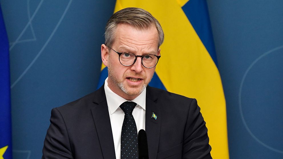 Bilden visar Inrikesminister Mikael Damberg (S) under en av regeringens presskonferenser. I bakgrunden syns svenska flaggan.