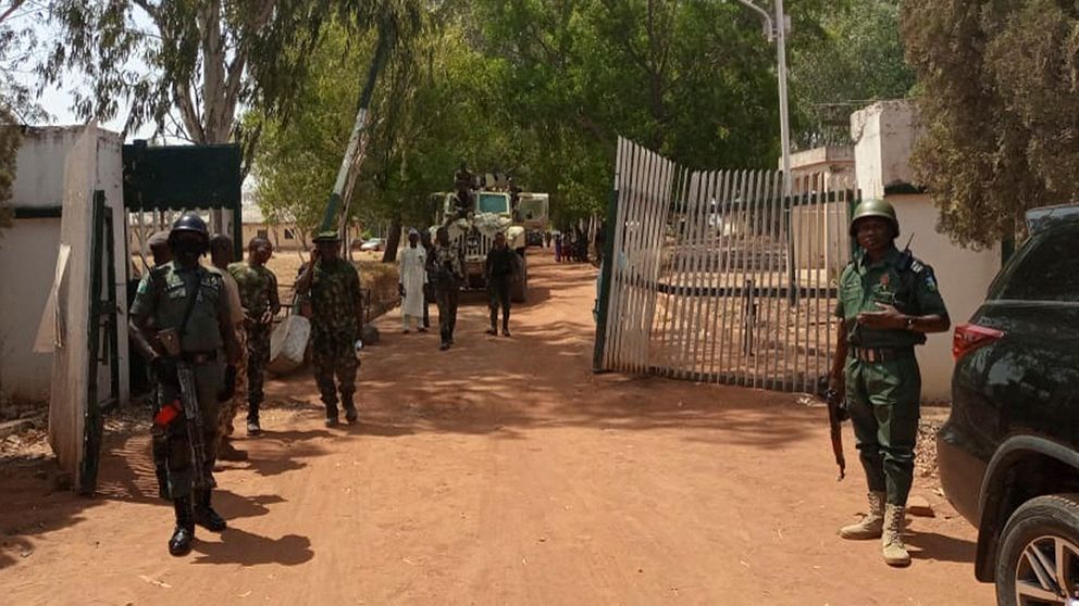 Militär och polis bevakar entrén till skolan i Nigeria där den väpnade attacken skedde.