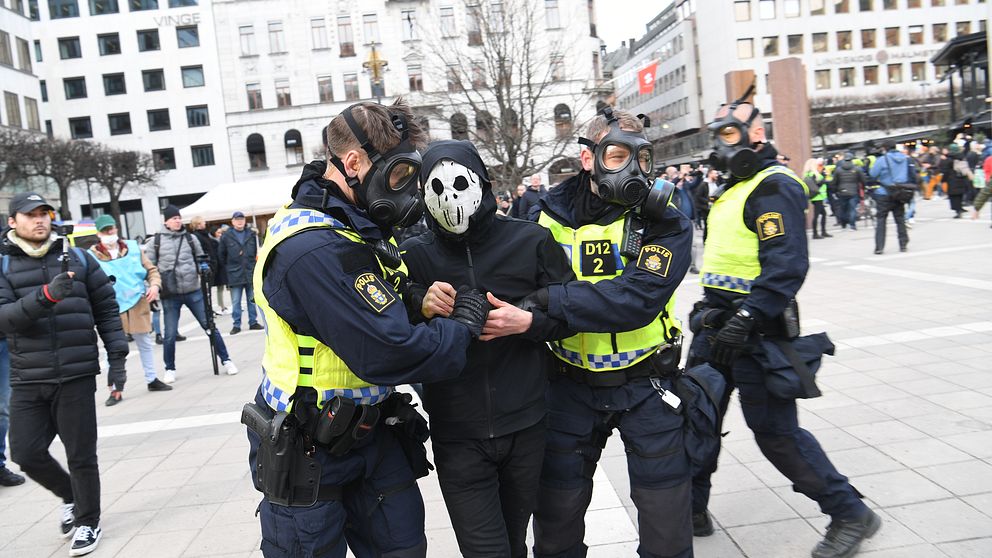 poliser i gasmasker bär bort en demonstrant i mask vid Norrmalmstorg efter en corona-protest