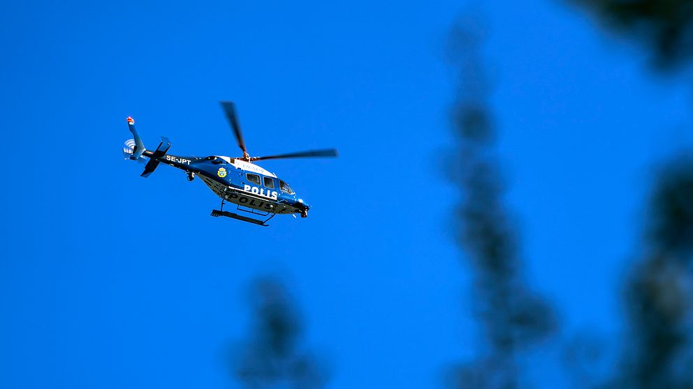 En polishelikopter som flyger mot en blå himmel.