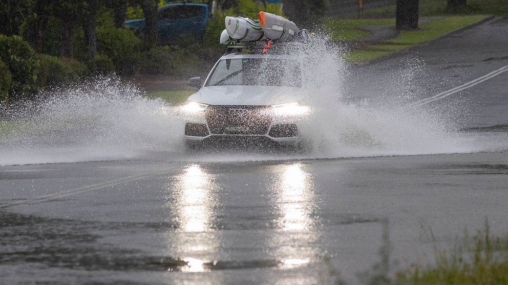 En bil kör i ett översvämmat Port Stephens, 20 mil norr om Sydney.