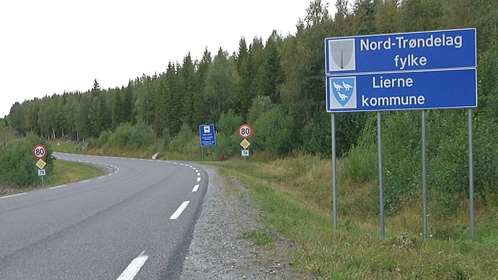 Asfaltsväg och blå vägskylt med texten Nord-Tröndelag fylke och Lierne kommune.
