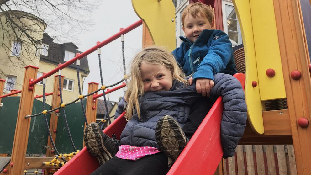 två barn i femårsåldern sitter i en rutschkana.