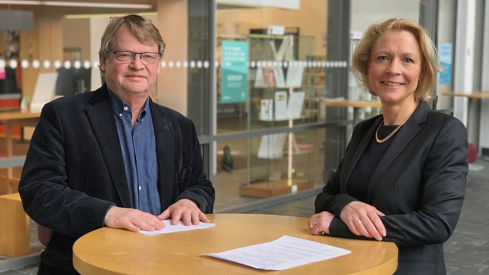 Rolf Solli och Anna Cregård vid ett ståbord framför biblioteket på Högskolan i Borås.