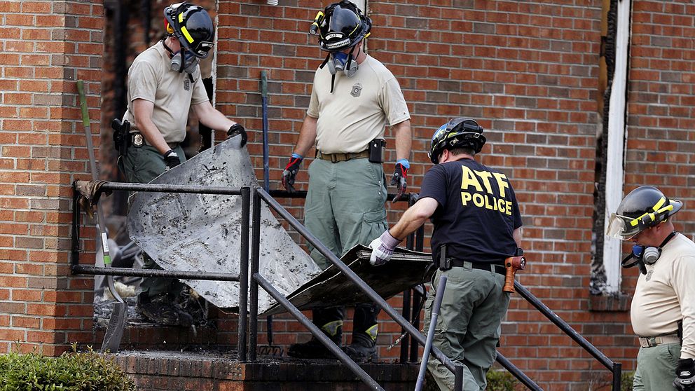 Amerikansk polis avlägsnar resterna av en dörr från kyrkan Mount Zion African Methodist Episcopal Church som brann under tisdagkvällen den 30 juni.