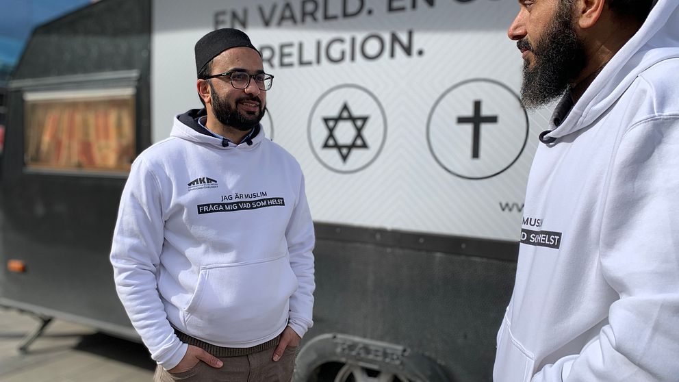 två imamer stående utanför sin turné husvagn