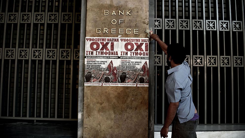 En man sätter upp nej-affischer på Bank of Greeces huvudkontor.