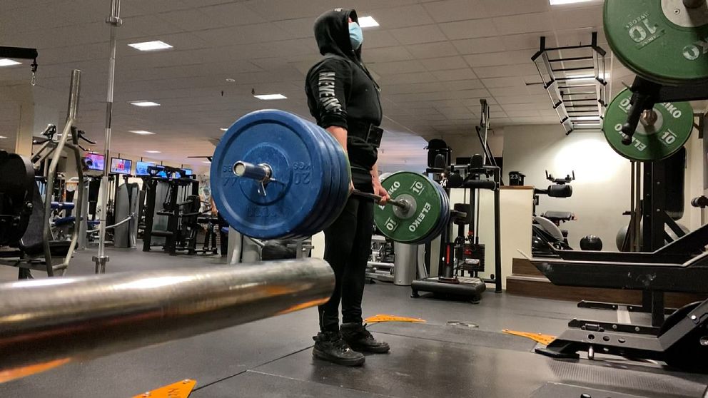 Samuel Johansson lyfter vikter, han väljer att bära munskydd på gym