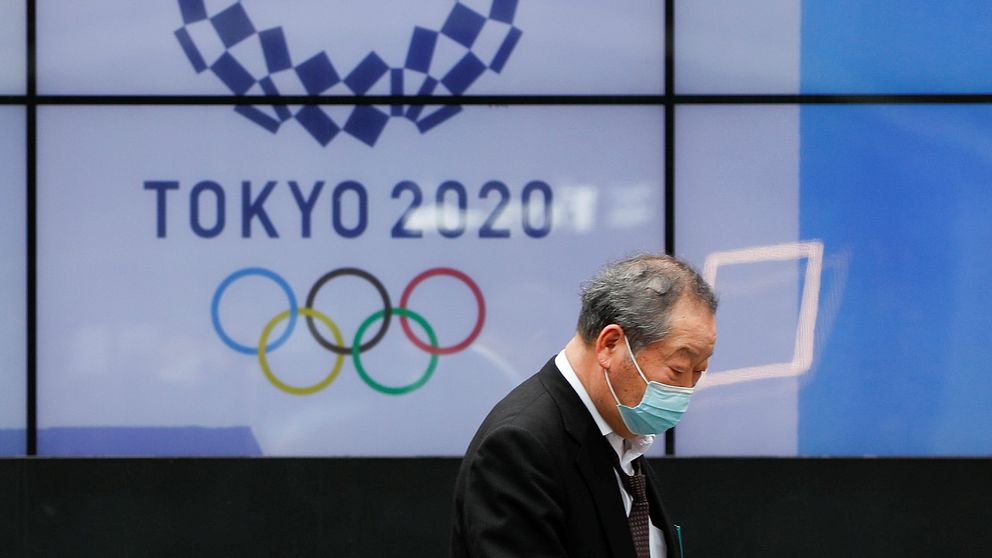 En förbipasserande man framför en av Tokyos OS-skärmar
