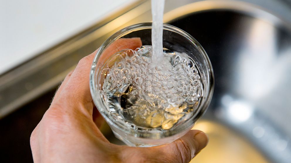 Vatten från en vattenkran som rinner ner i ett dricksglas.