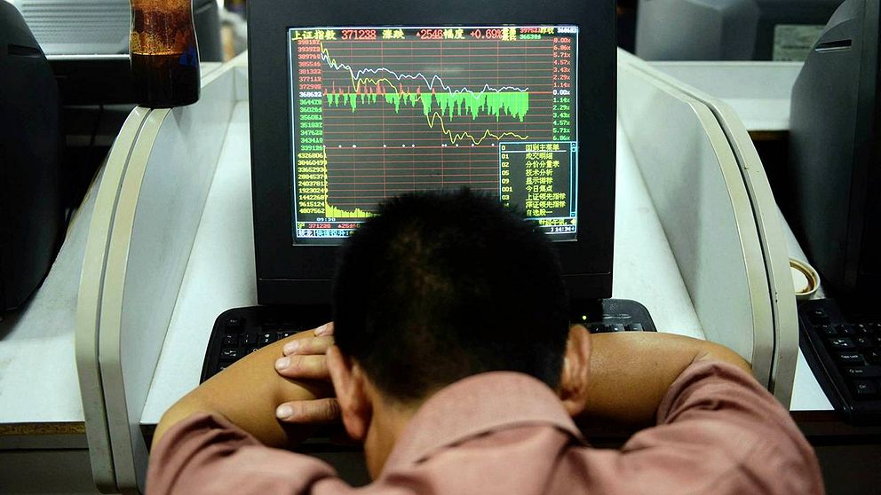 En handlare på Shanghaibörsen sjunker ihop framför sin skärm när kurserna bara faller. Bilden är från den 6 juli – i dag har kurserna dykt ännu mer. Shanghaibörsen föll nästan 7 procent vid öppnandet.