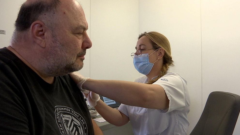 Levent får en spruta i armen av sjuksköterskan som bär munskydd