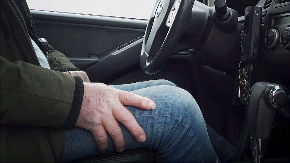 Man sitter med sin hand på knät i förarsätet på en bil.