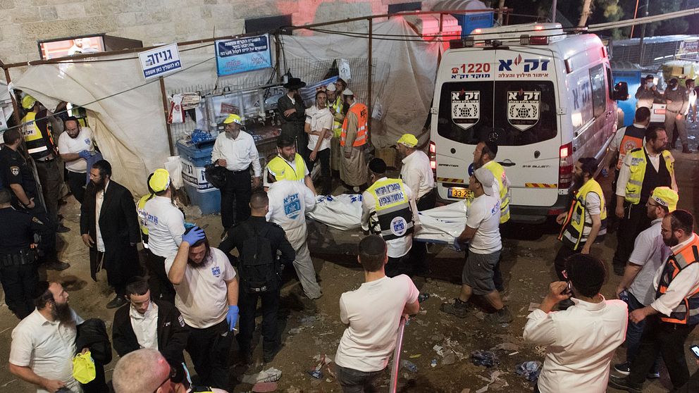 En av de döda bärs bort under räddningsinsatsen i Israel. Räddningspersonal vittnar i Israeliska medier om att det var så mycket folk på plats att det var svårt att komma fram till alla skadade.