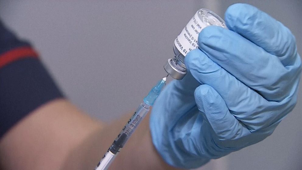 Vaccinpersonal drar in vaccin i spruta från ampull.