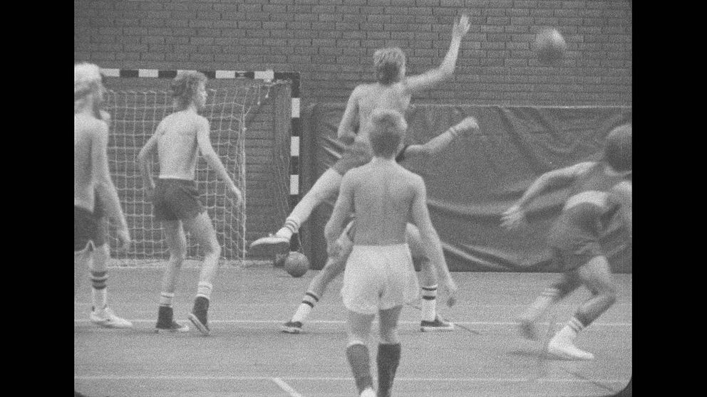Svartvit bild på unga män i bar överkropp som tränar basket i sporthallen i Östersund.