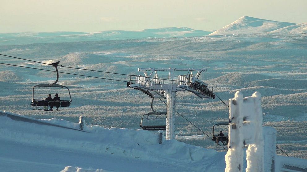 Vinterbild på skidlift med skidåkare i. I bakgrunden fjällmassiv.