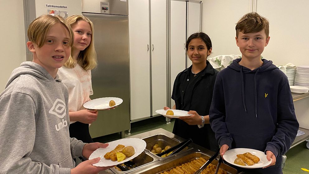 Fyra skolelever som plockar mat i en skolmatsal