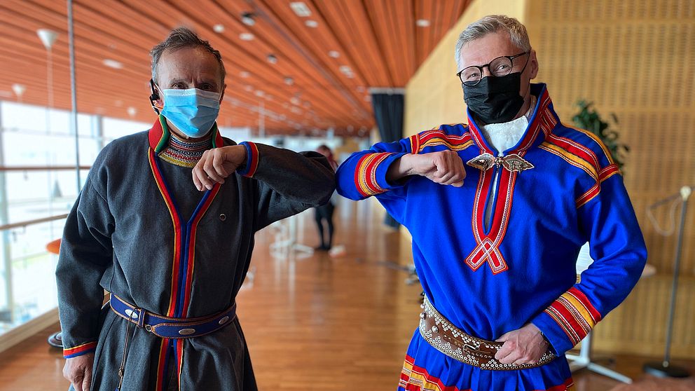 två män i samekolt och med munskydd gör corona-riktig ”armbågshälsning”