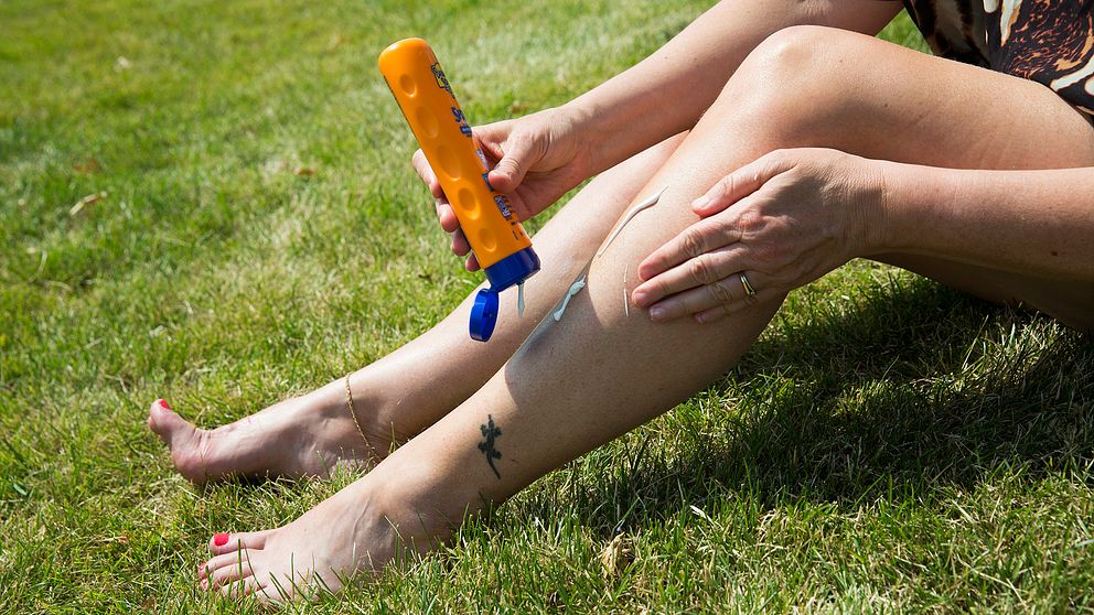 Kvinna smörjer in sina ben med solkräm.