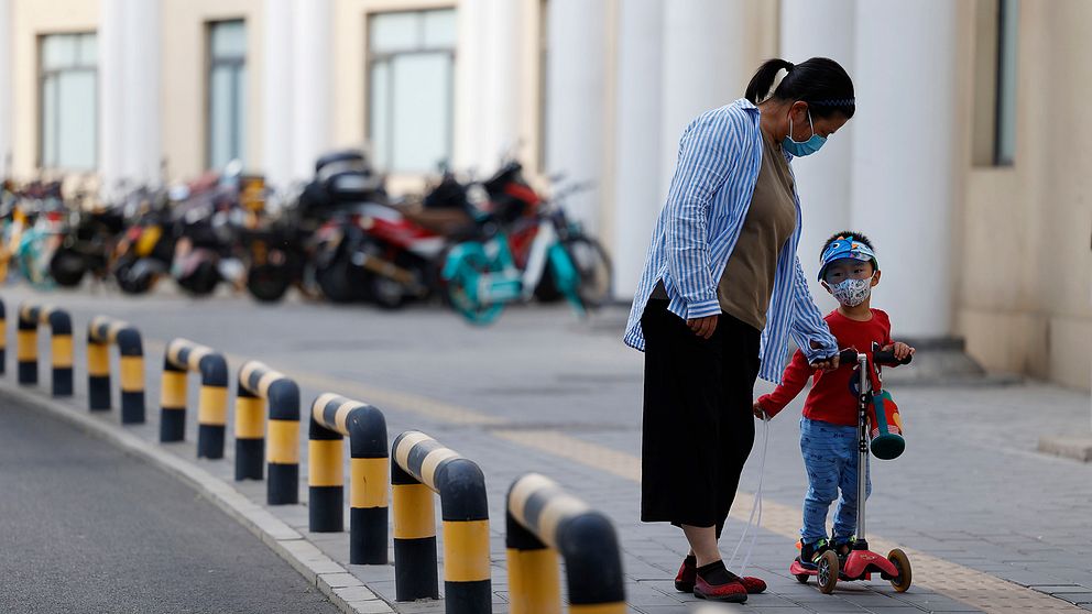 Kinesisk mamma med barn på sparkcykel.