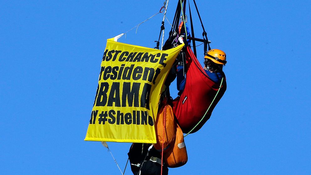 En greenpeaceaktivist hänger upp banderoller i Portland, USA.