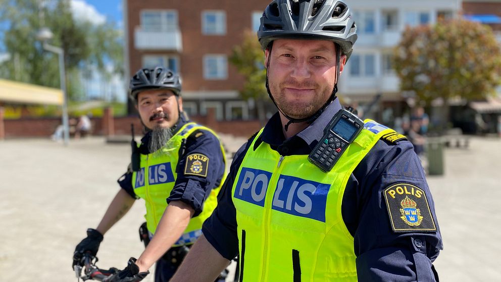 närbild två manliga poliser i cykelhjälm på ett torg