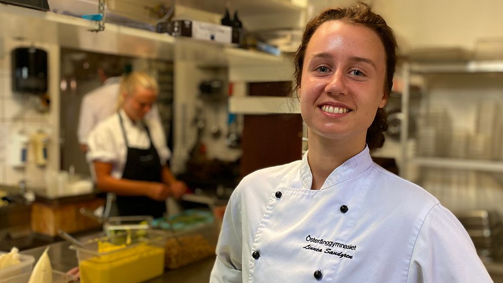 Kvinna med kockrock i ett restaurangkök