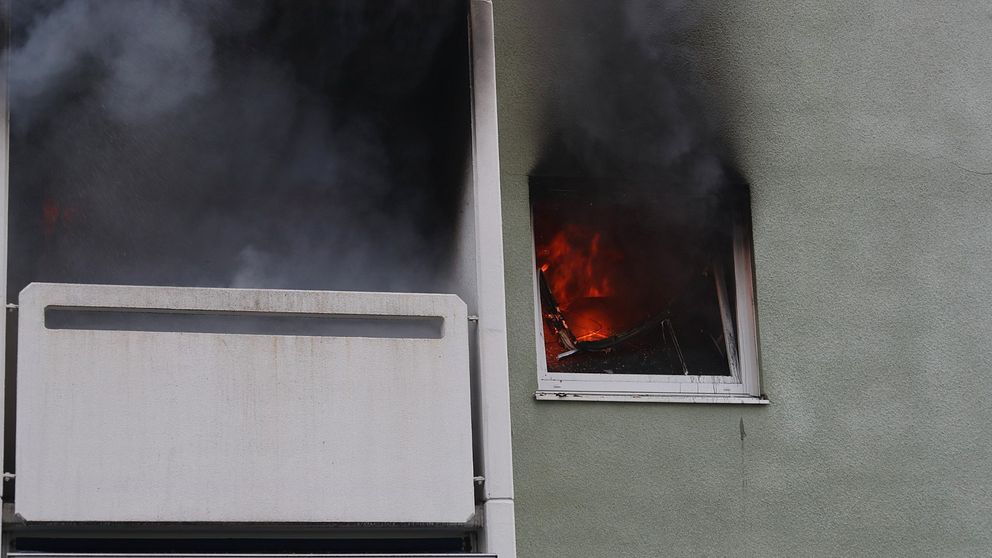 Rök sväller ur ett fönster i en byggnad.