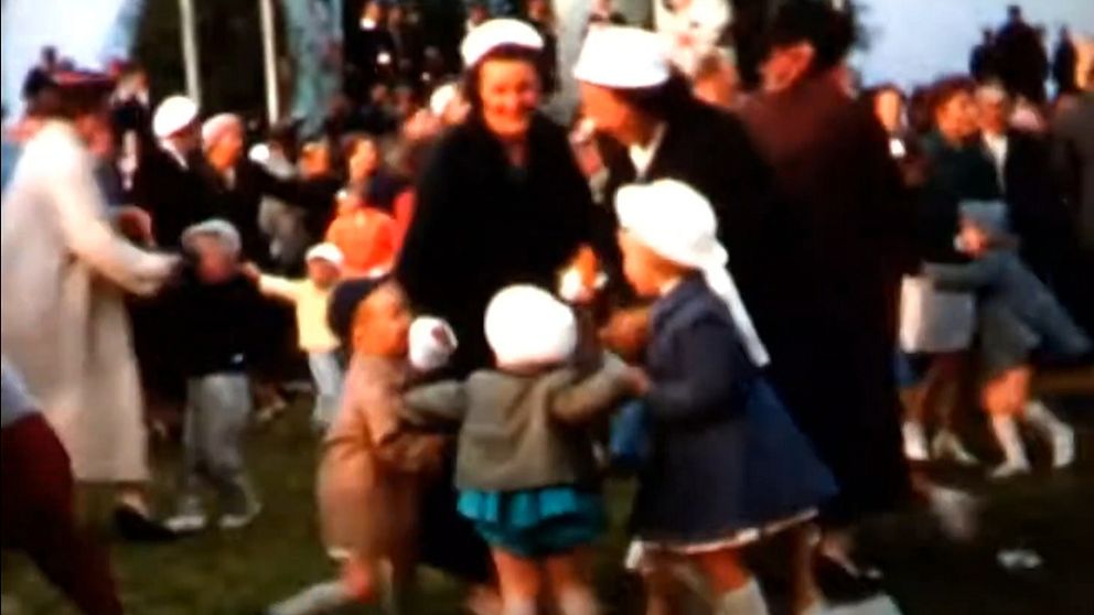 Bild på kvinnor och barn som dansar på en midsommarfest 1957-