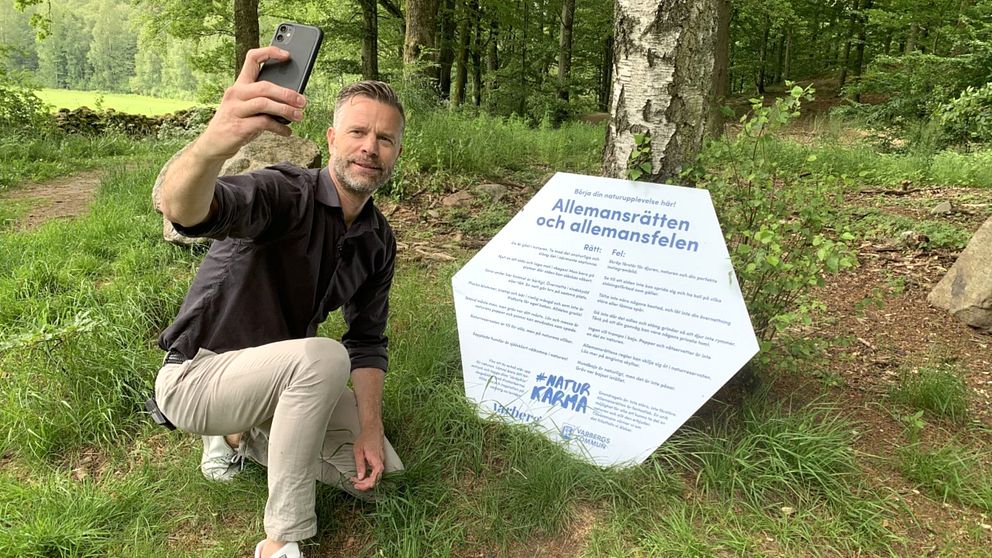 Näringslivsdirektören i Varbergs kommun, Martin Andersson, poserar framför en av de skyltar som satts upp i Åkulla bokskogar. Den informerar om vilka rätt och fel man kan göra i naturen.