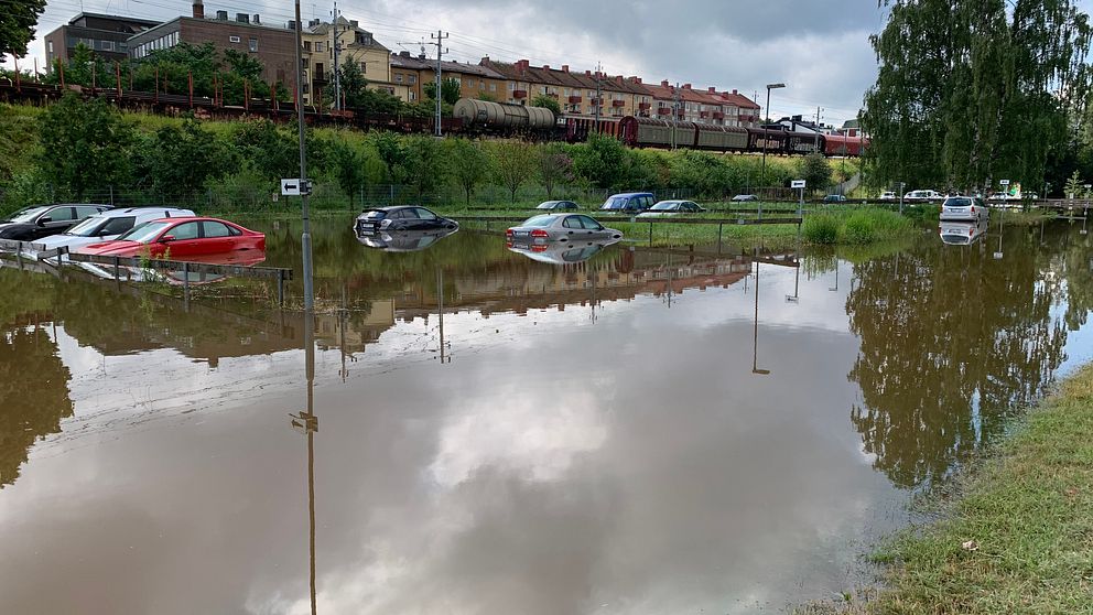 Bilar på en parkeringsplats, bilarna står i meterhögt vatten så går ända upp till rutorna.
