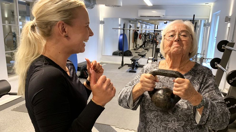 88-åriga Inga-Lill Johansson från Varberg lyfter en kettlebell under uppsyn av sin personliga tränare Carolina Enberg.