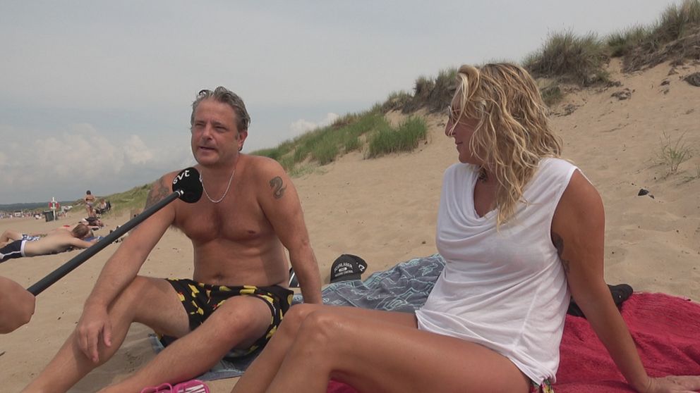 Therese Ericsson och Magnus Lindqvist sitter på varsin handduk på stranden och tittar mot svt-micken.