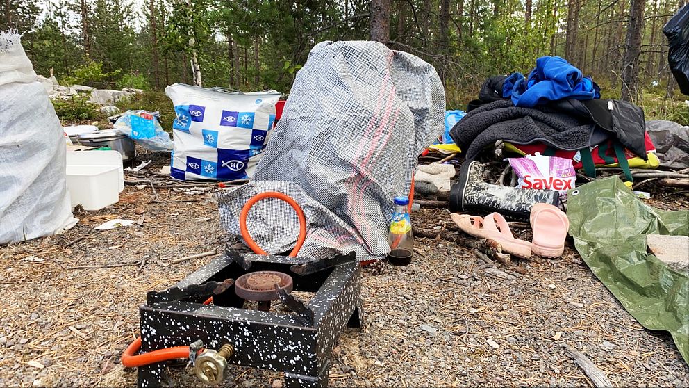 Ett tältläger med plastpåsar, en gammal gasspis och skräp.