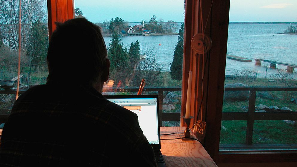 En man jobbar vid sin dator framför ett fönster.