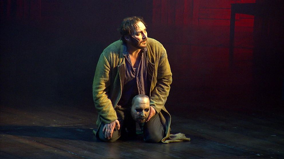 Skådespelaren Jakob Hultcrantz sitter på scen med en ansiktsmask i handen ur föreställningen Körkarlen