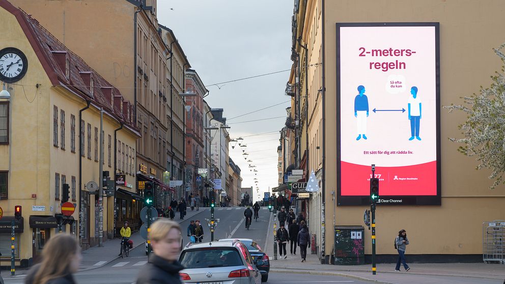 En stor skylt i centrala Stockholm uppmanar folk att hålla 2 meters avstånd.