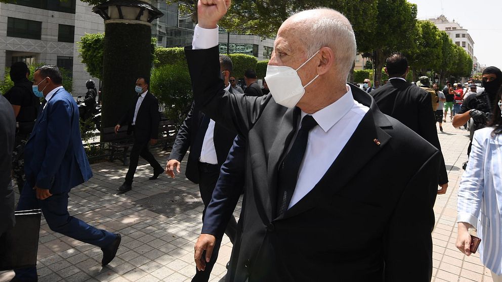 President Kais Saied gesturing among supports as he walks protected by security guards