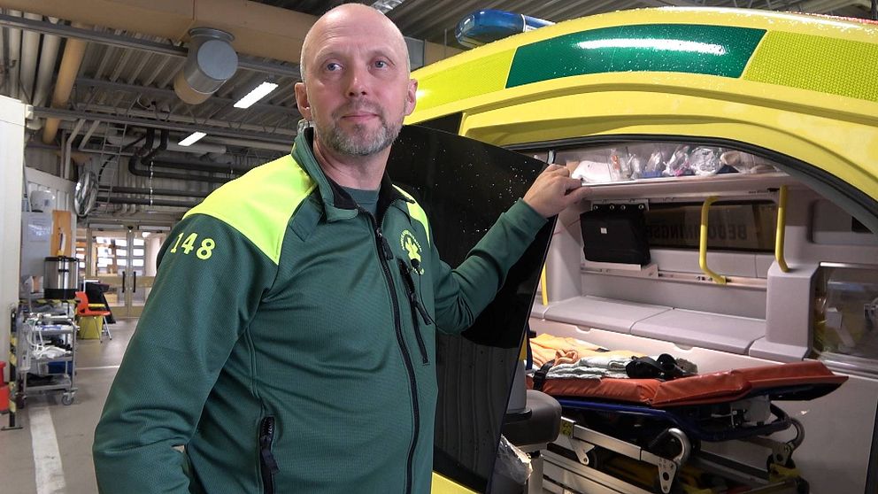 en man i ambulansens kläder vid en öppen ambulans i garage