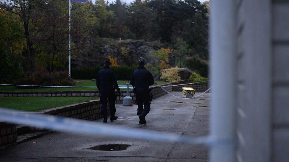 Två polismän utanför en lägenhet.