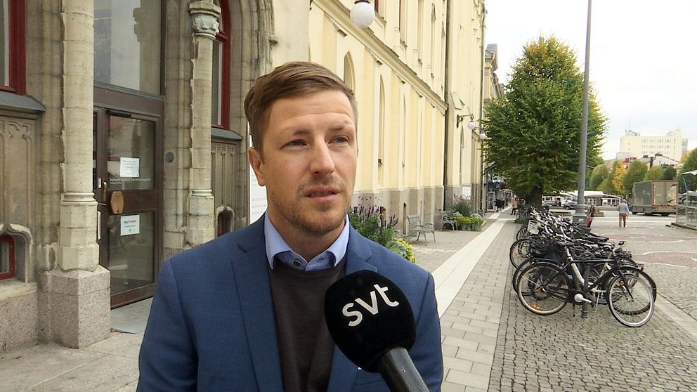 På bilden står Jimmy Nordengren utanför Rådhuset i Örebro, Han är klädd i blå kostym med en svart tröja under och en blå skjorta som sticker fram under kragen.