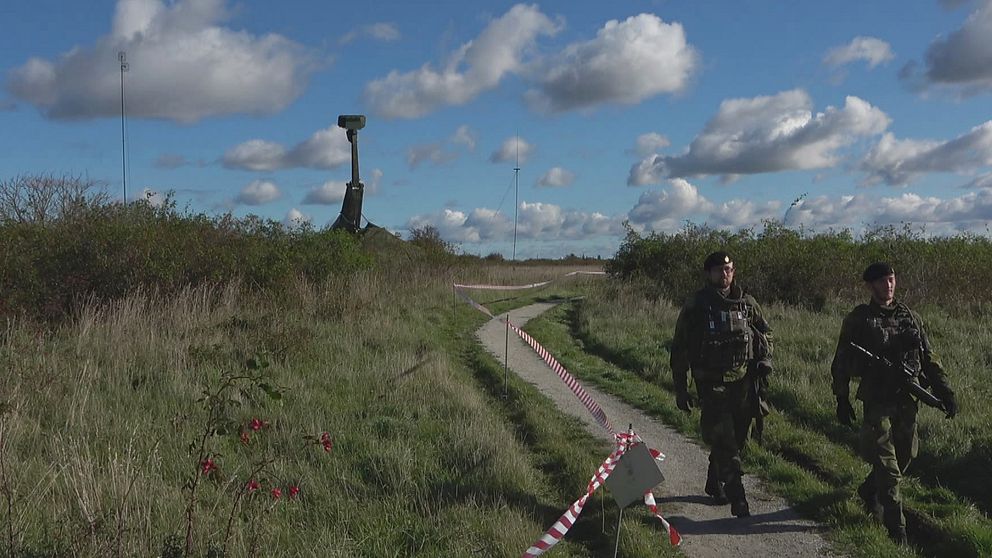 Två militärer som går beväpnade på en stig i Klagshamn natureservat med en radar i bakgrunden som bevakar luftrummet över Malmö.